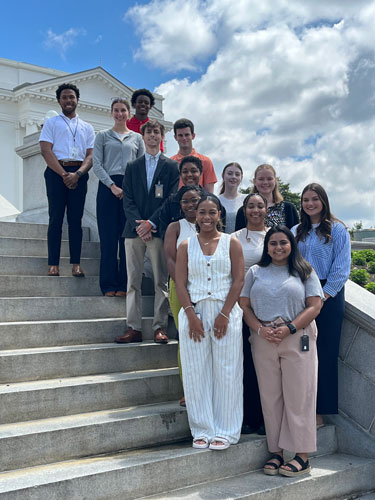 grupo ng mga estudyanteng nakatayo sa hagdan ng Kapitolyo